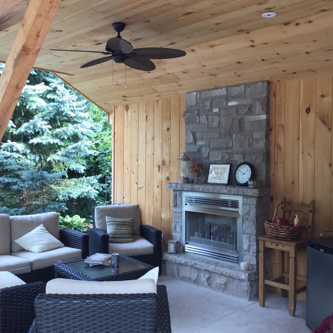 outdoor fireplace with fan on the ceiling and outdoor seating nearby photo by Instagram user @country_estates_landscaping