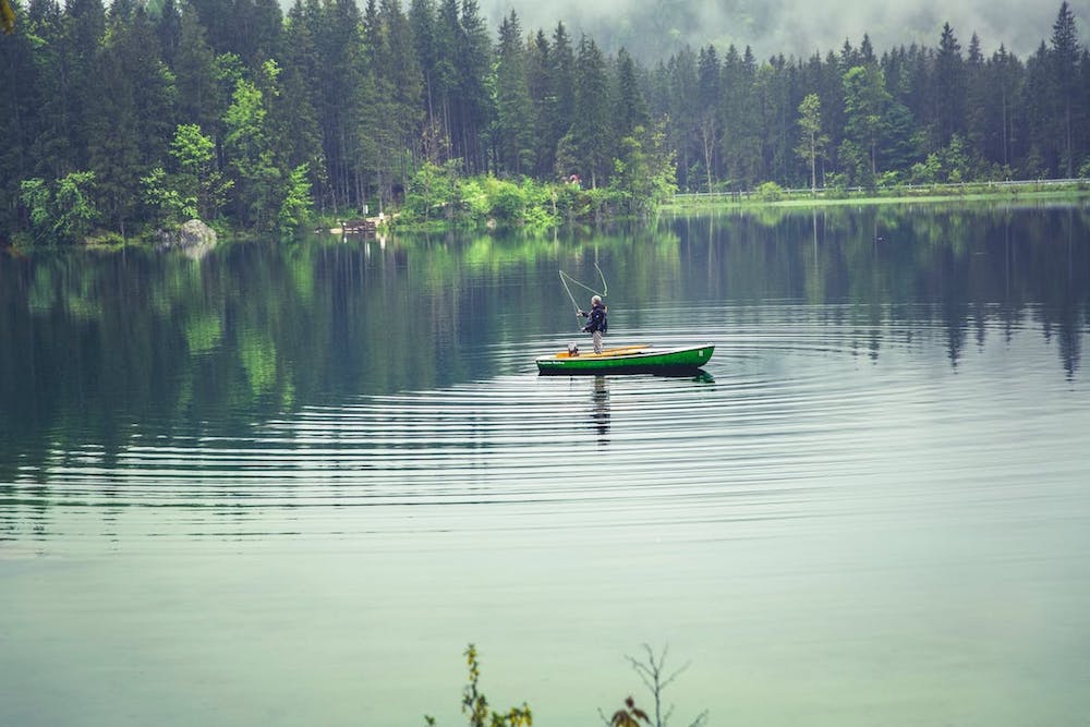 Man in fishing boat in center of lake