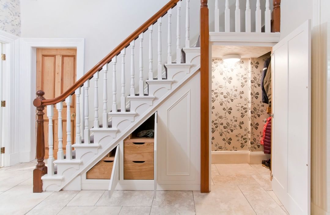 Under stairs closet with coats hanging up and smaller cabinets.