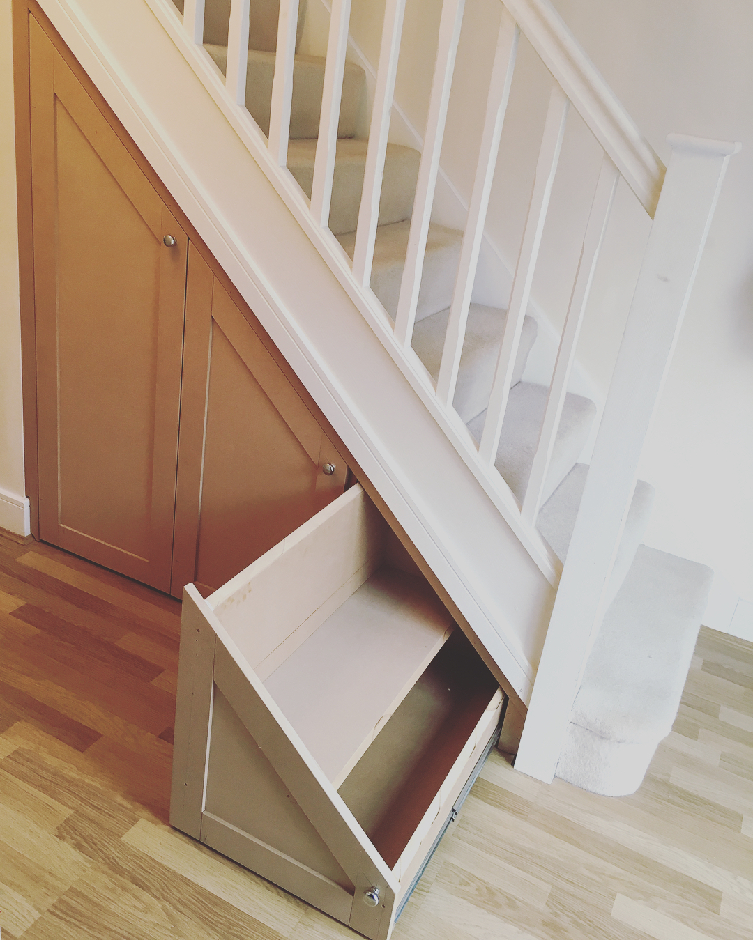 Sliding drawer added beneath stairs in the home.
