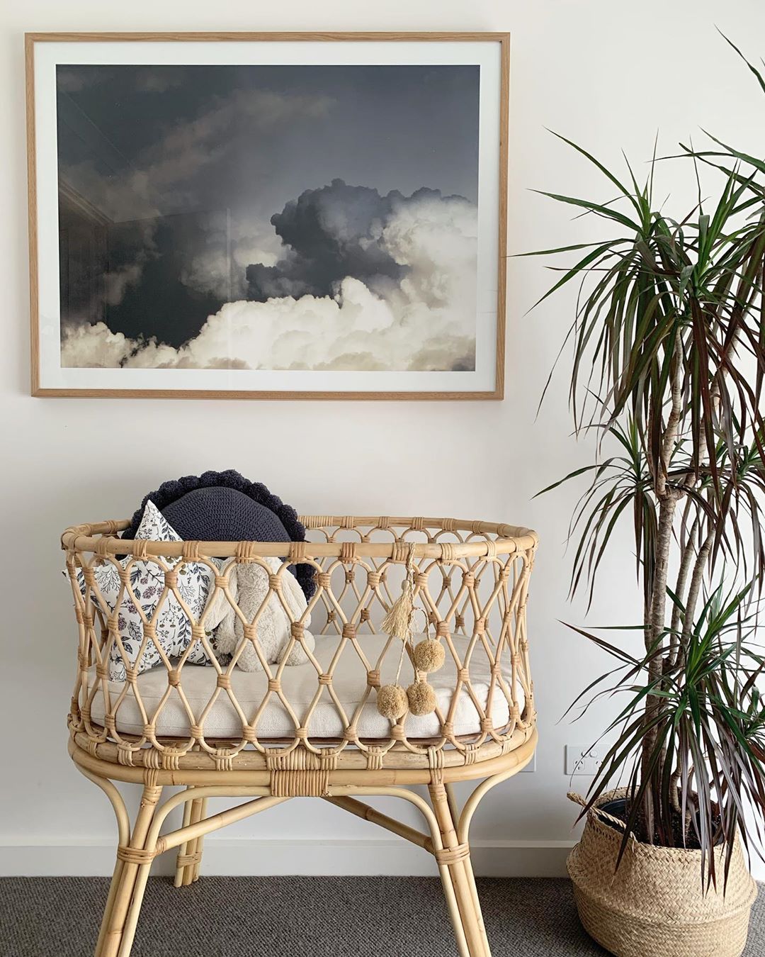Bassinet under painting next to plant. Photo by Instagram user @derived_by_design