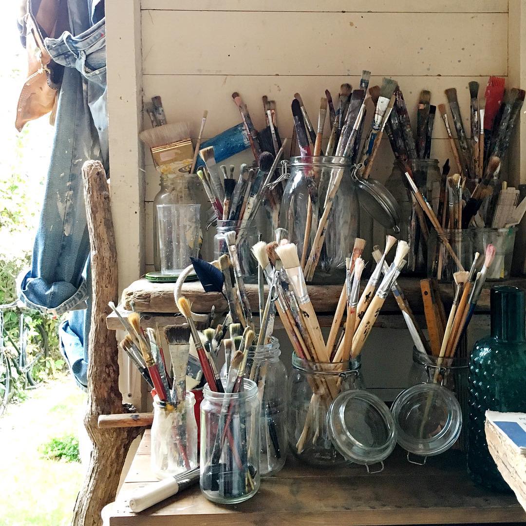 extra paint brushes being stored in old mason jars photo by Instagram user @silverpebble2