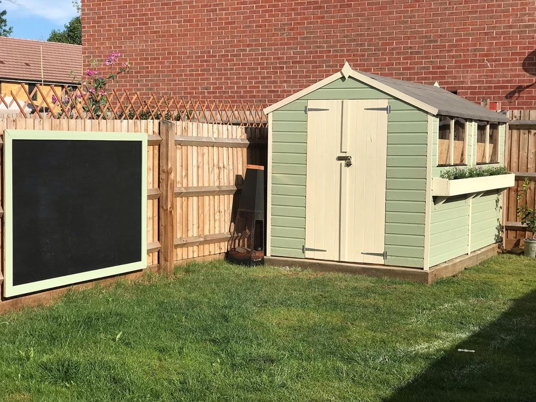 large chalkboard hung on the fence outside small garden shed photo by Instagram user @ourfirsthome54