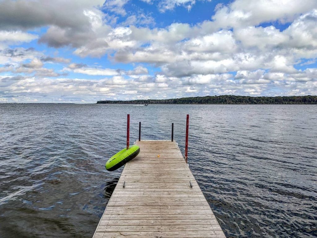 A pier with an inner tube on it above a dark blue lake on a cloudy day. Photo via Instagram user @lucid_lefty