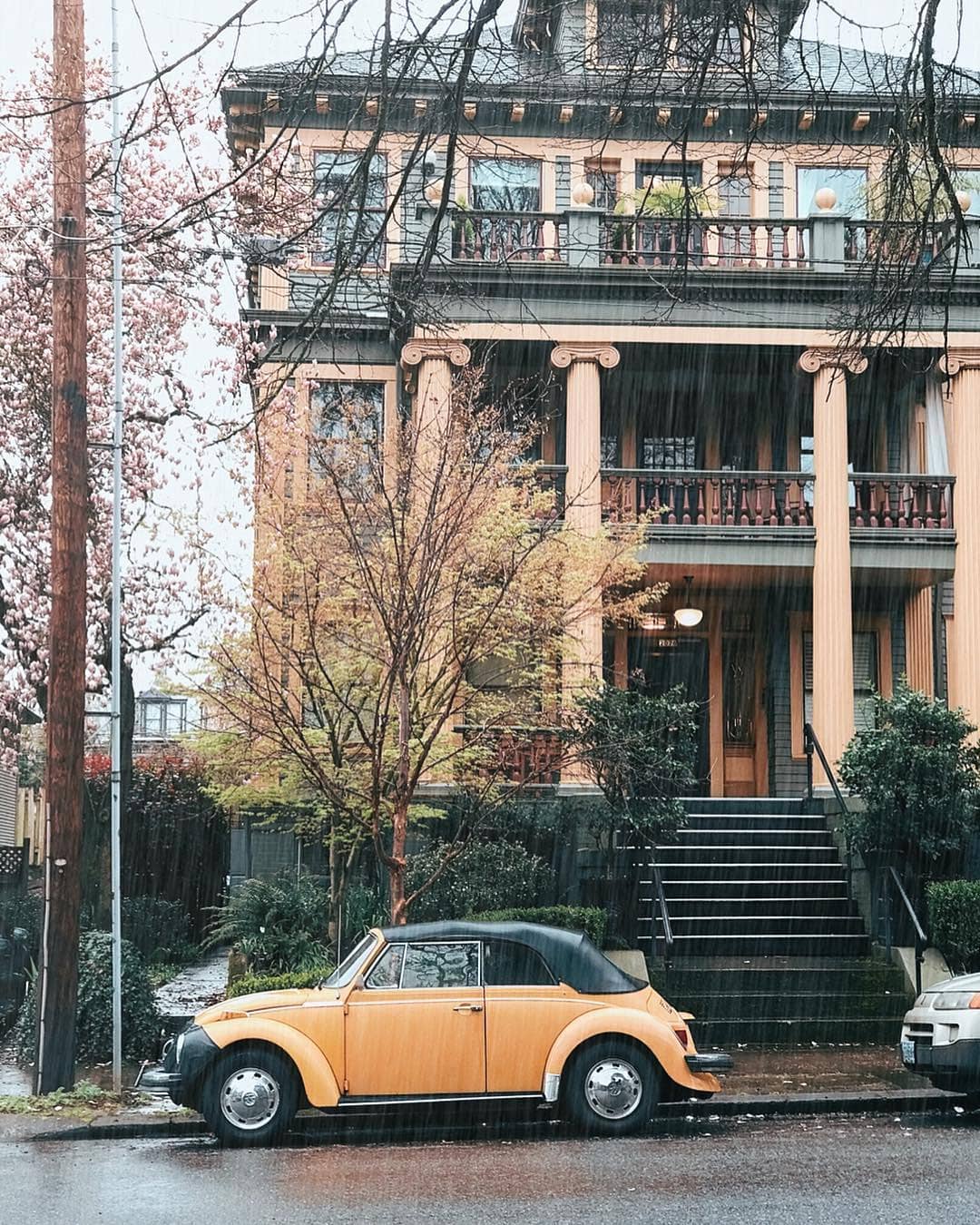 Front view of large three-story home with pillars in front and a VW Beetle parked on the street in front. Photo by Instagram user @portlandcreatives