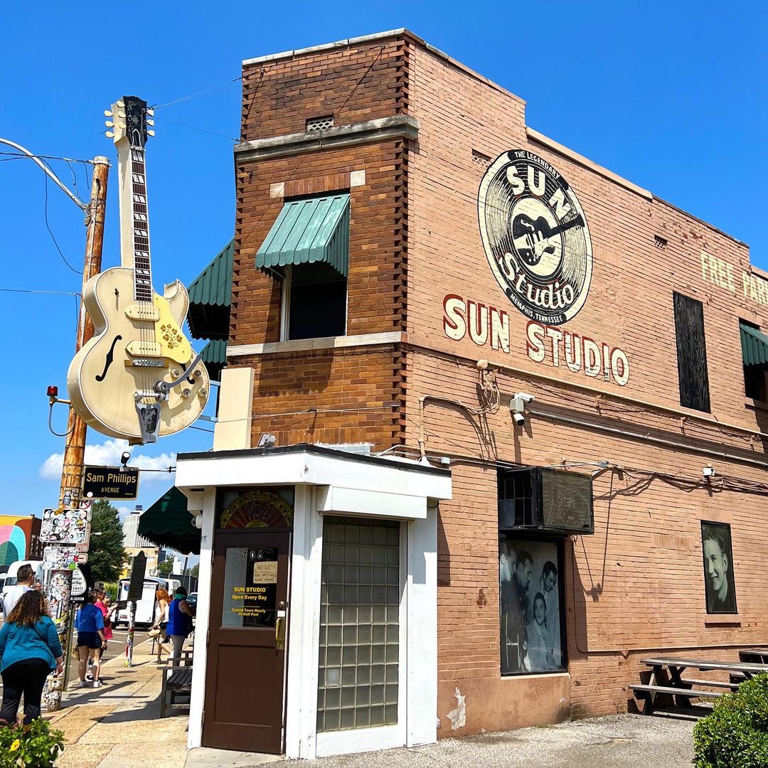 Sun Studio brown brick building on corner of street with brown door and white trim entrance below hanging guitar in Memphis. Photo by Instagram user @billfelty