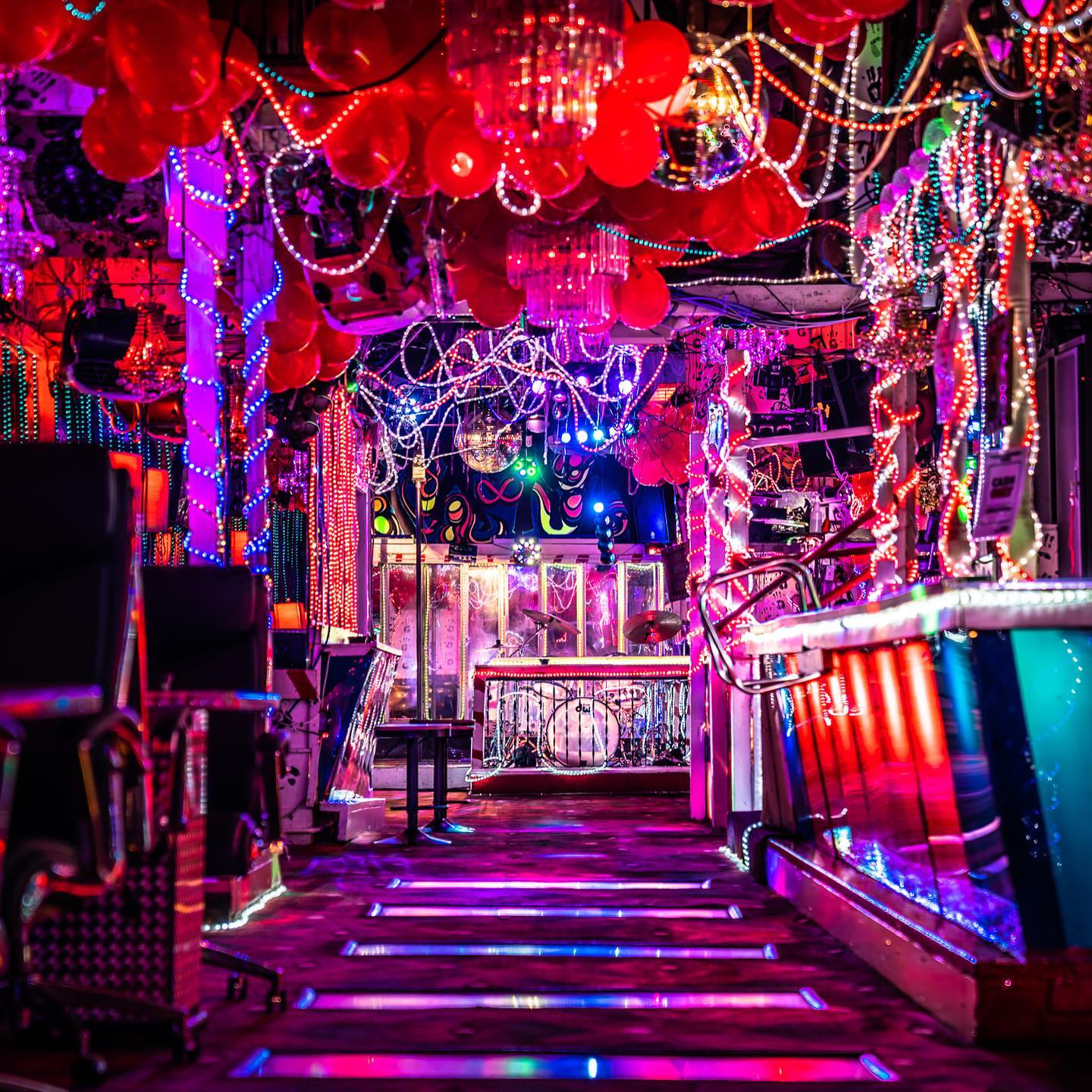Photo of Paula and Raiford's Disco bar with neon lights, illuminated bar, drum set, and red balloons and disco ball on the ceiling. Photo by Instagram user @darrellderosia