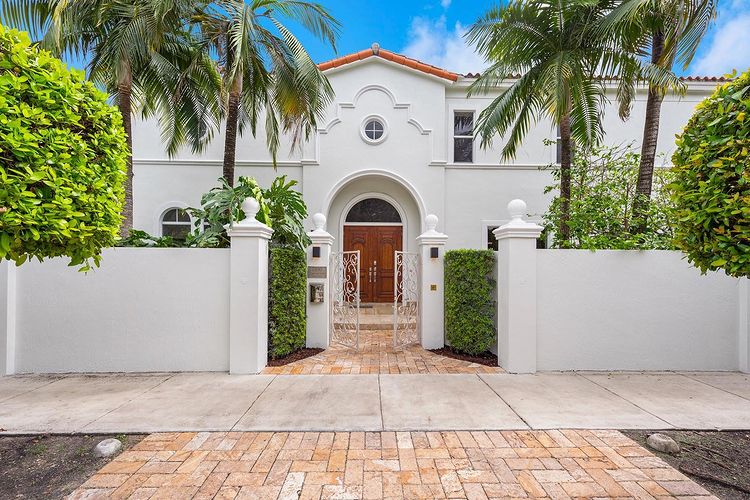 White spanish-style home with front wall and palm trees. Photo by Instagram user @nancybatchelorteam