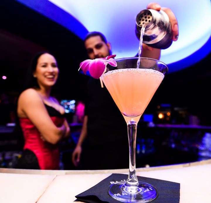 Bartender pouring a fruity martini with woman standing next to him. Photo by Instagram user @bluemartinilounge
