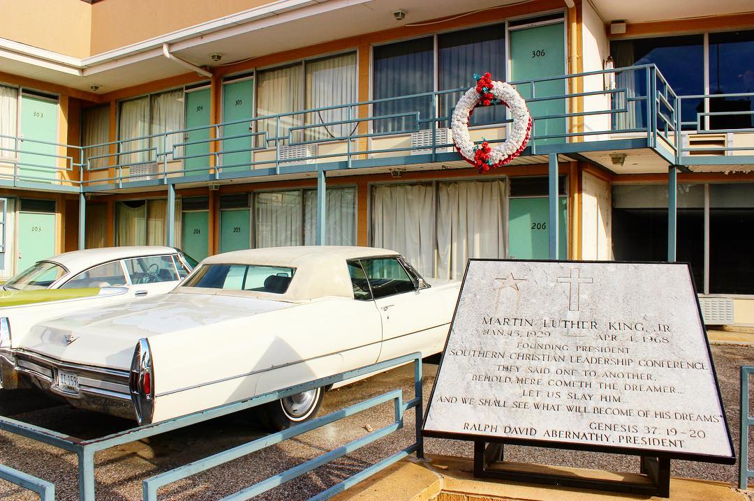 The Lorraine Motel and Martin Luther King Jr memorial plaque next to two cars and wreaths hangs from motel railings. Photo by Instagram user @licornephotography