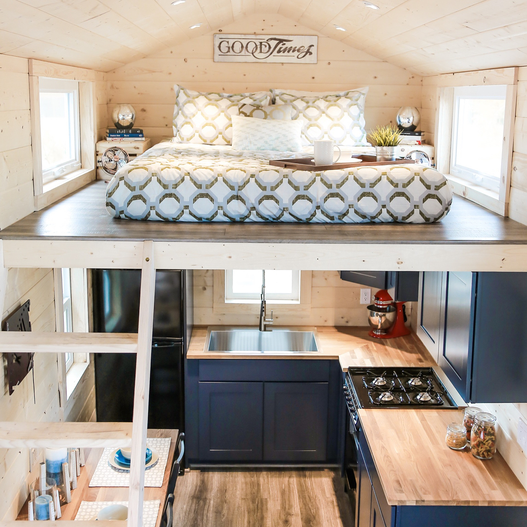 Tiny home with bed lofted above kitchen. Photo by Instagram user @unchartedtinyhomes