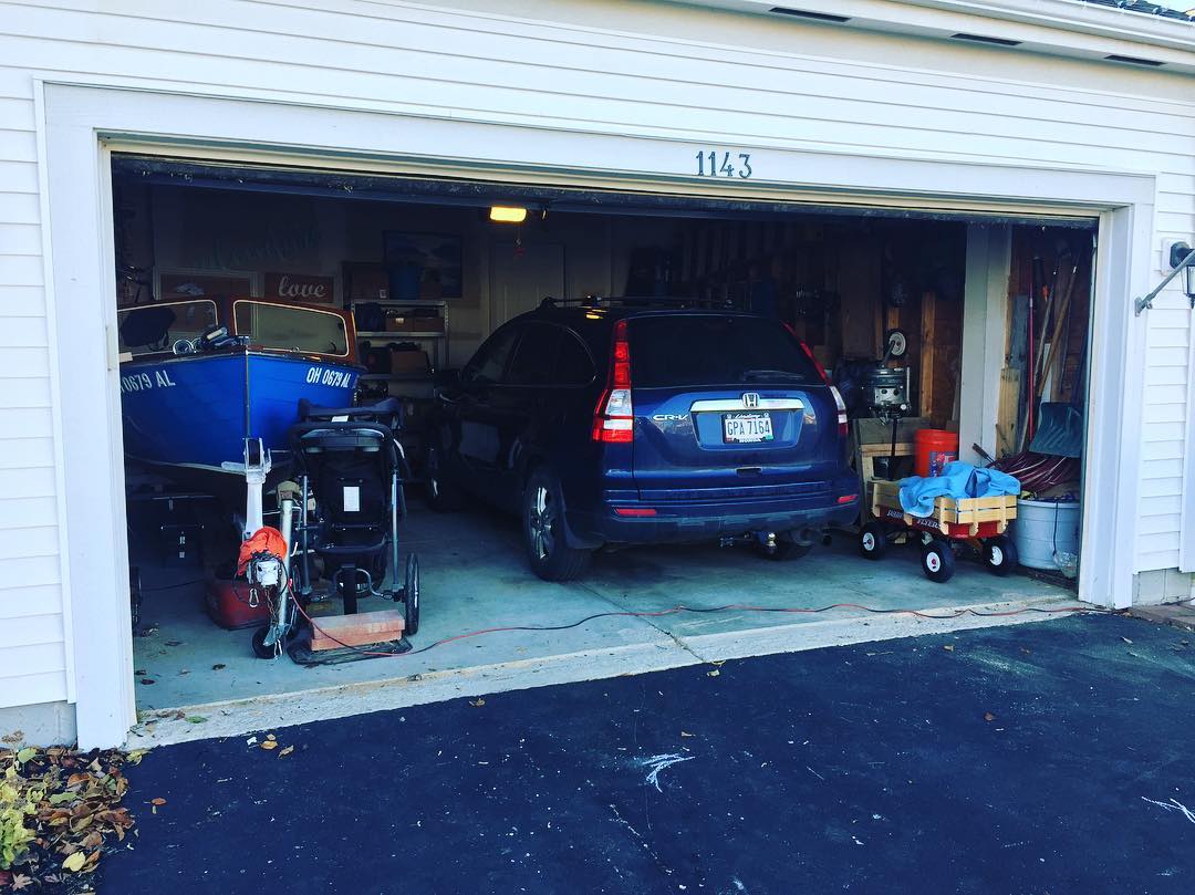 boat being stored in home garage with car next to it photo by Instagram user @revivalwoodworks