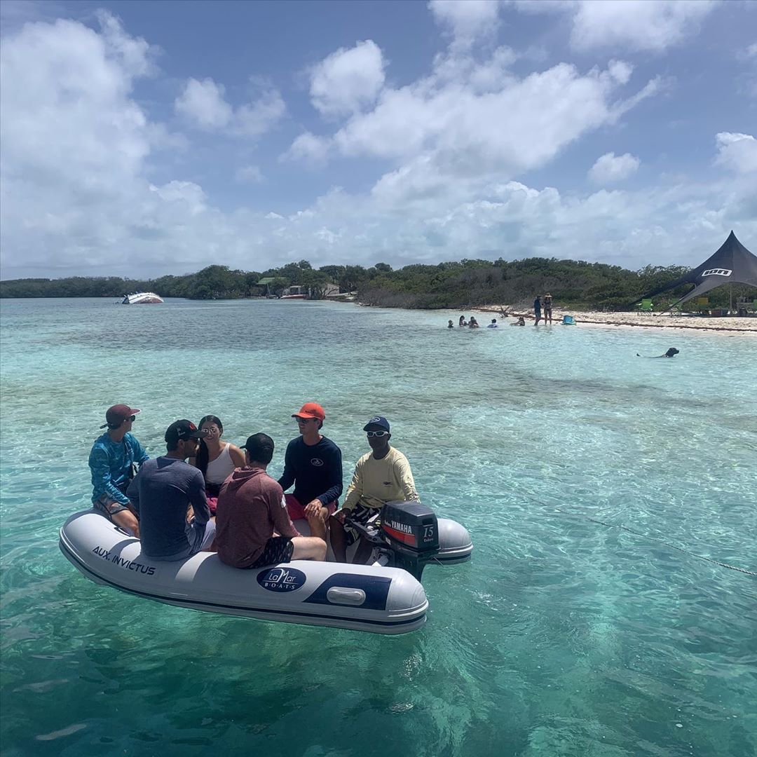 multiple people sitting on the sides of a dinghy in clear water photo by Instagram user @lamarboats