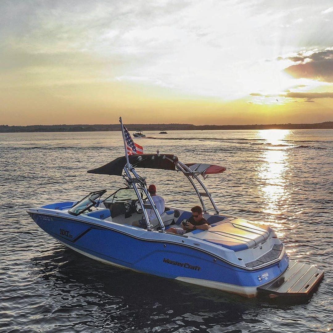 blue tow sports boat with American flag attached in the water at sunset photo by Instagram user @djdingz