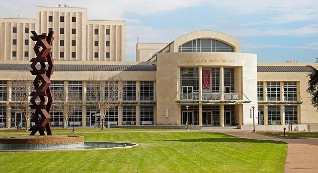 Front view of the MD Anderson Library, green spaces, sidewalks, and an outdoor sculpture at the University of Houston. Photo via Instagram user @uhadvamb
