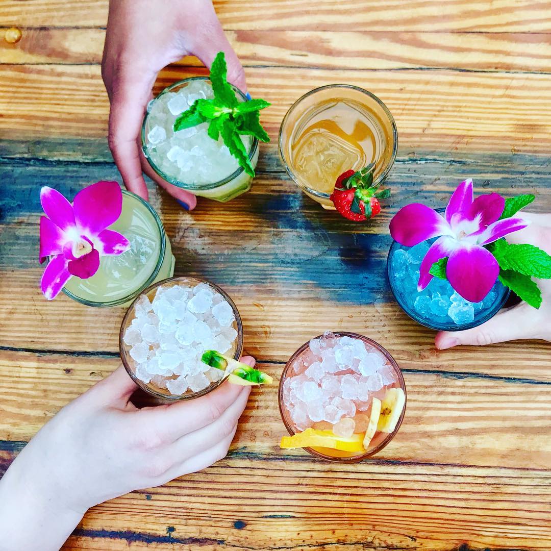 Overhead View of Six Different Alcoholic Drinks with Flowers and Herbs on Top. Photo by Instagram user @roofatparksouth