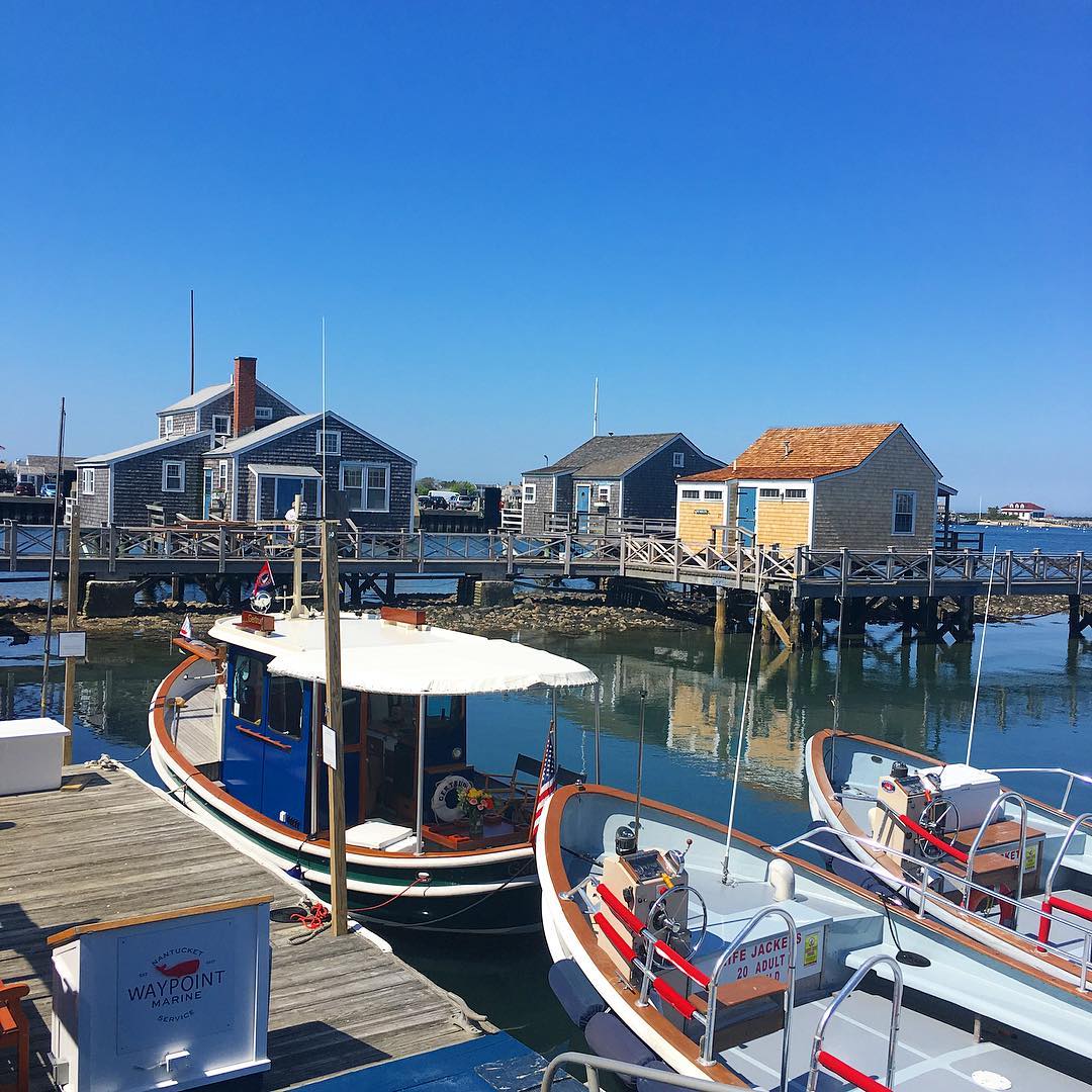 Boats on a Dock with Cottages in the Background at the Nantucket Boat Basin. Photo by Instagram user @thecottagesnantucket