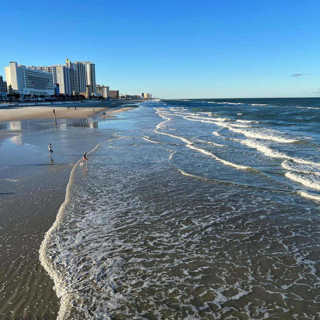 Waves breaking on wet sand with a city skyline in the back. Instagram photo by @david.ruizrivera