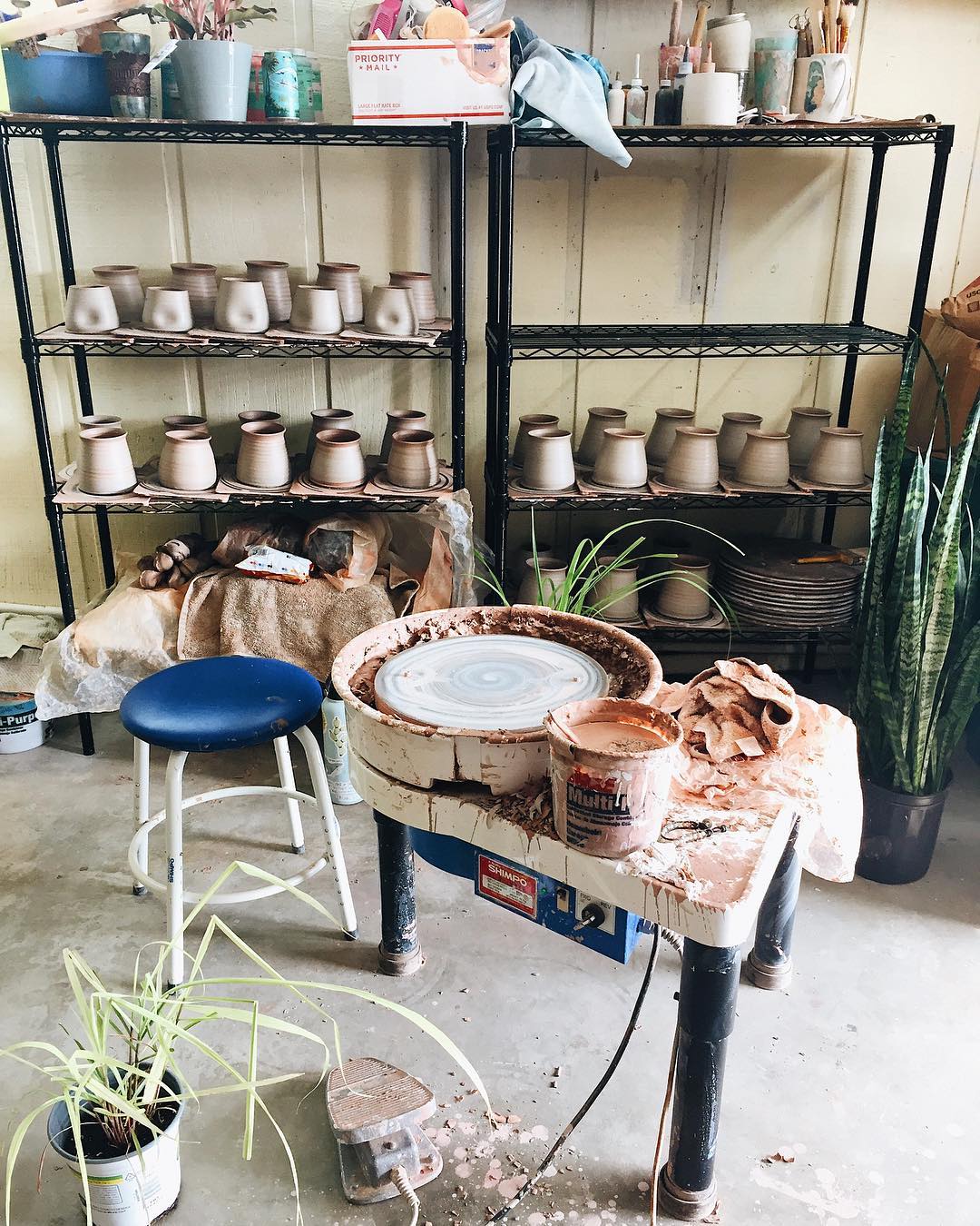 garage ceramics studio with wheel set up and shelves with supplies photo by Instagram user @swellceramics