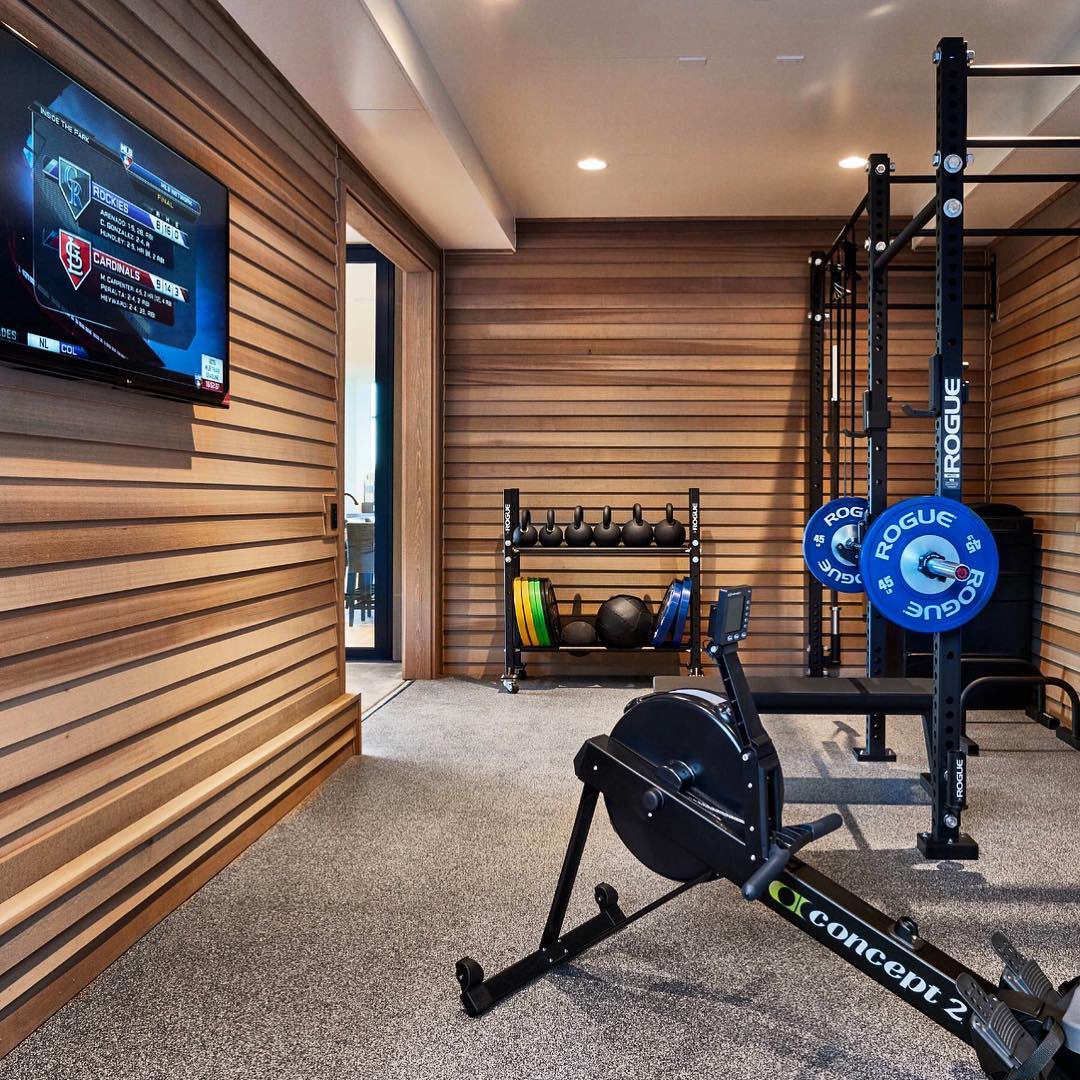 Home fitness room with weights, rowing machine, and TV. Photo by Instagram user @ajestudio