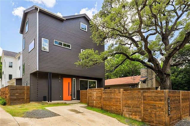 modern gray two-story home with orange door and wooden fence. photo via @kentravis.sells.austin