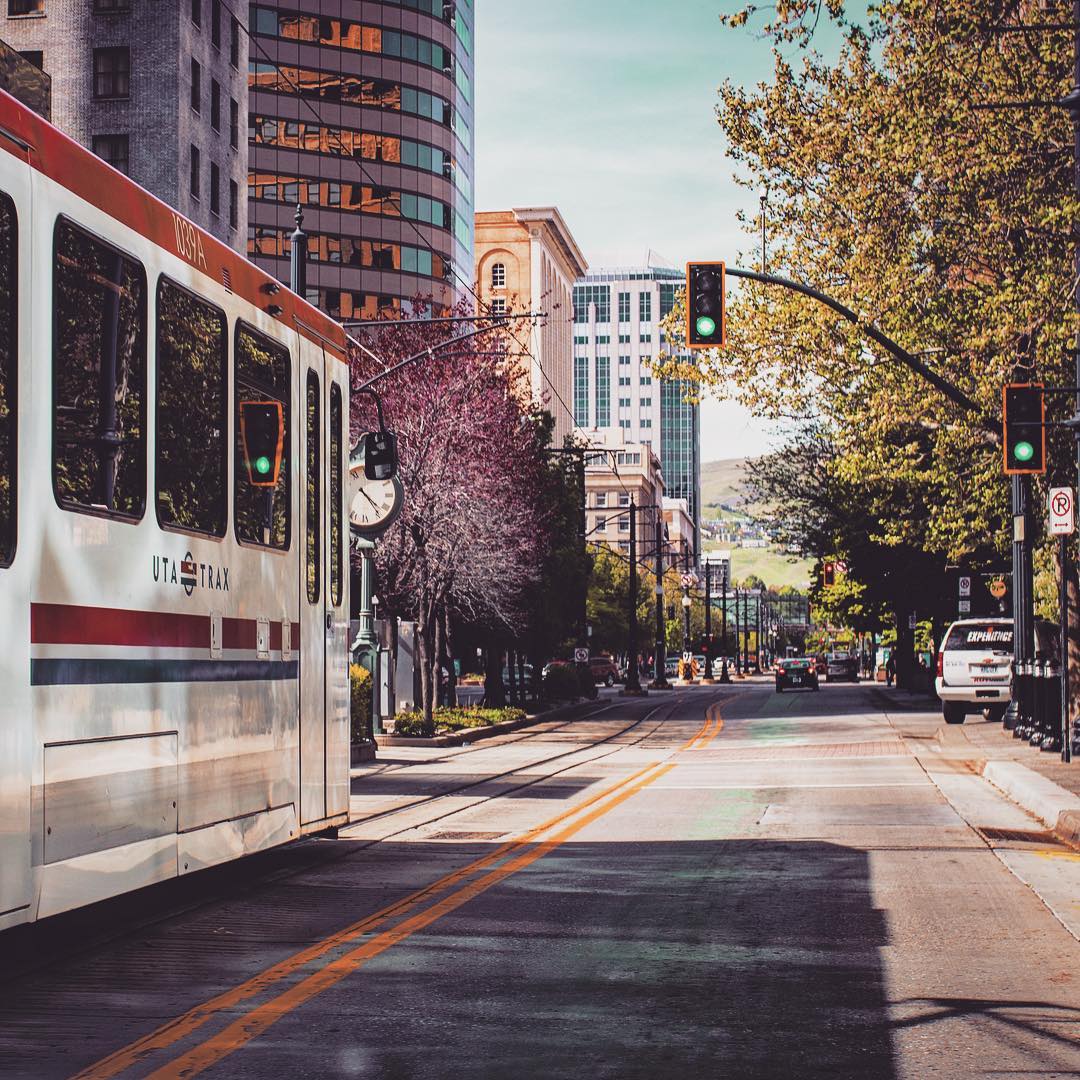 View of a rail car moving down the street with tall buildings on the right side and open space on the left. Photo by Instagram user @blacksmith.international