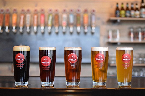 A flight of beer in glasses sit atop the bar table ranging from dark to light. Photo by Instagram user @uintabrewing