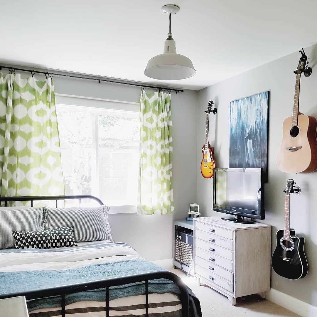 small bedroom with bed and instruments hanging on the wall photo by Instagram user @homeofjuniper