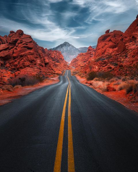 Dark road leading into red rock mountains. Photo by Instagram user @mo.shotss