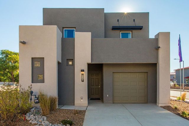 A modern style adobe home with brown and grey blocks of color. A yard of river rock, mulch, and tall grasses populates the foreground. Photo via Instagram user @twilight.homes