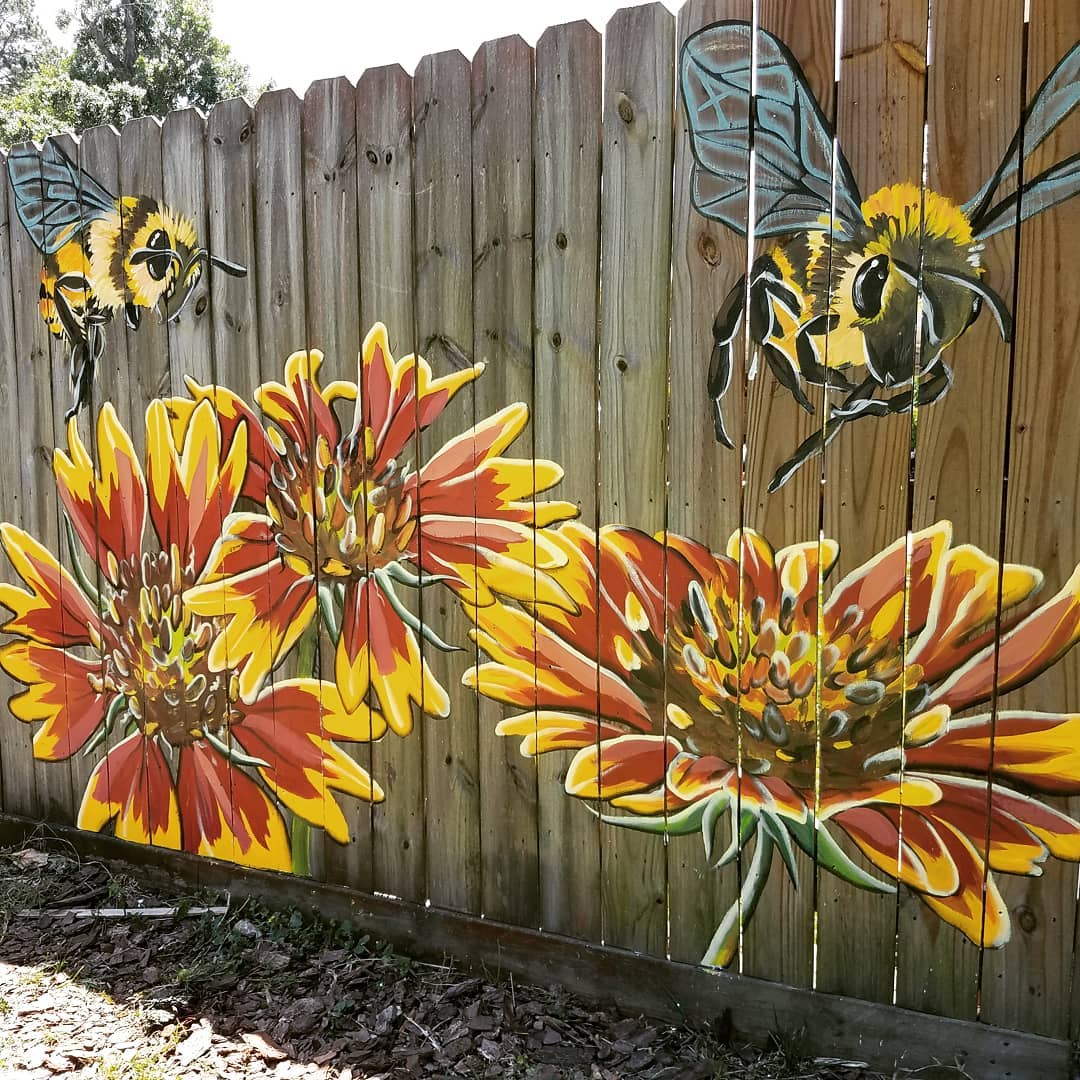 Red and yellow flowers and a bee fence mural. Photo by Instagram user @bettysmith.art