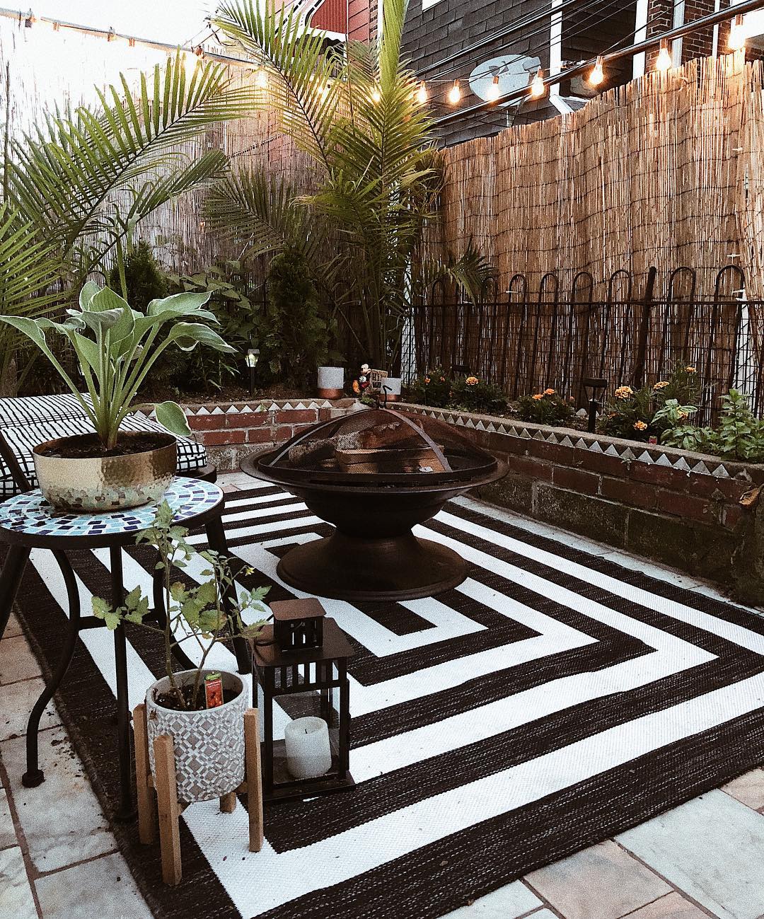 Patio with fire pit and black and white rug. Photo by Instagram user @alexandmike