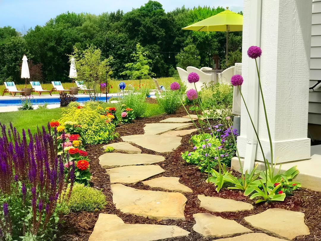Outdoor stone path lined with flowers. Photo by Instagram user @plaids.and.poppies
