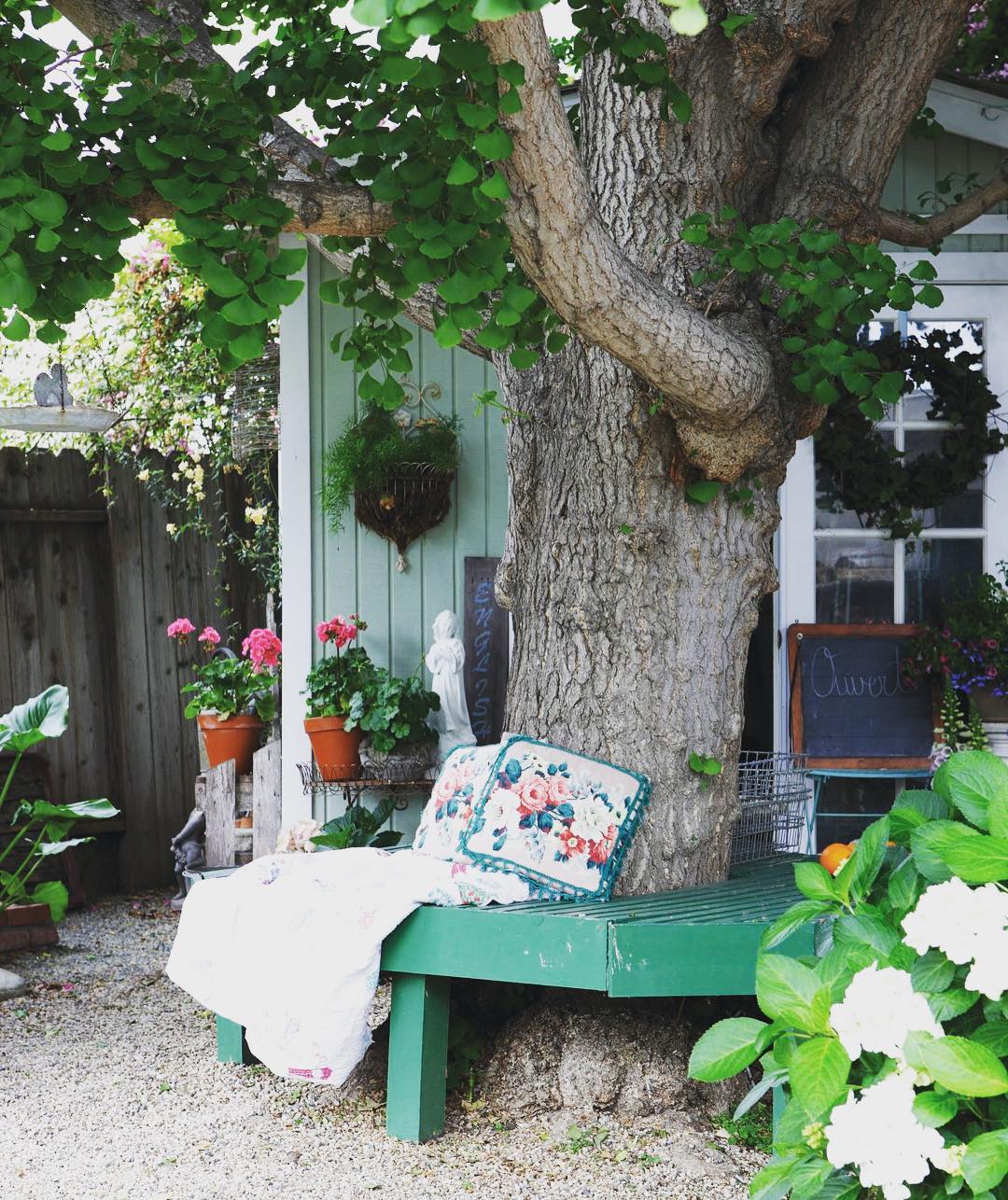 Green bench that wraps around a tree. Photo by Instagram user @cottagesandbungalows