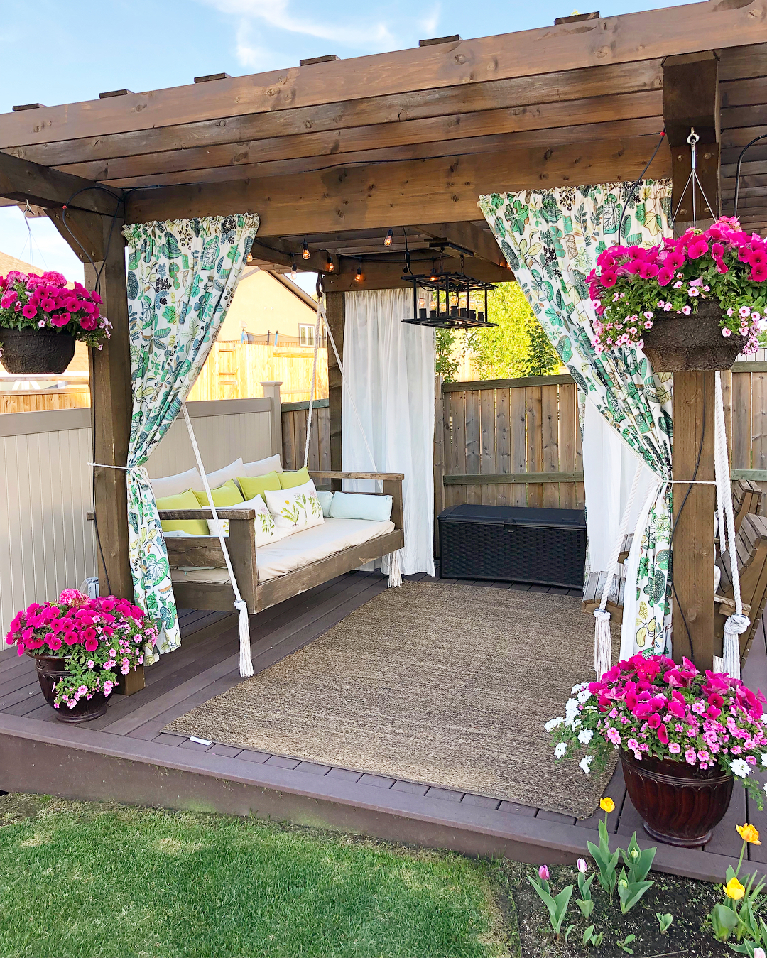 Pergola draped with floral curtains and pink flowers. Photo by Instagram user @wainwrighthousetohome