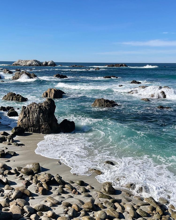 Blue-green ocean water tides flowing over sand and rocks on a beach. Photo by Instagram user @katelynclaire