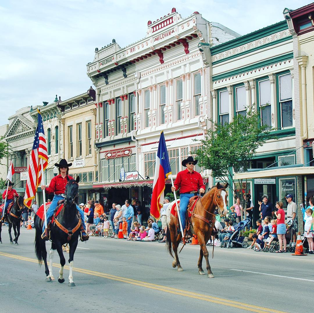 people on horses riding on main street holding texas state flag and american flag photo by Instagram user @georgetowntx
