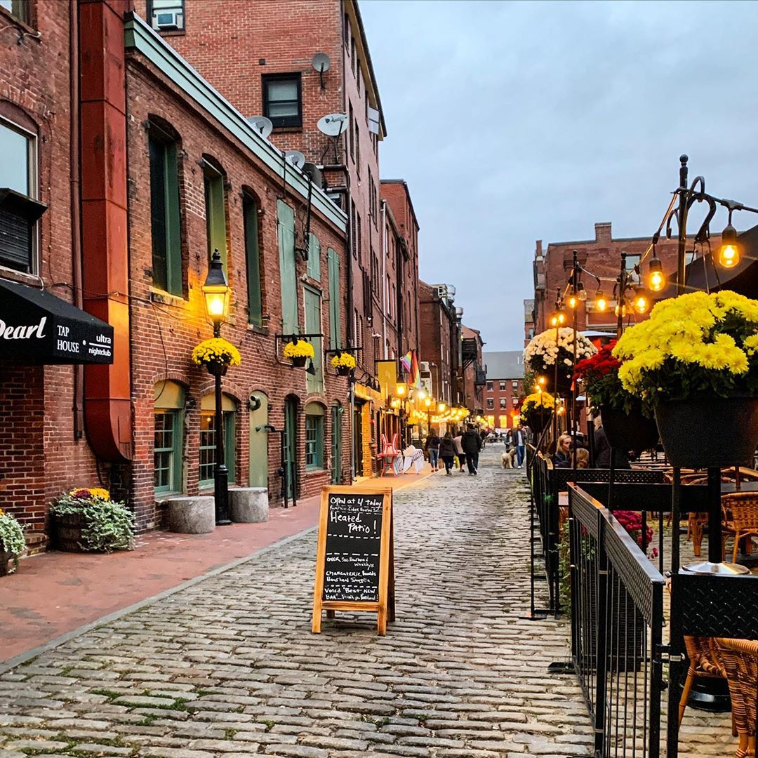 cobblestone street with brick buildings at night in Portland, ME photo by Instagram user @thisplaceinmaine