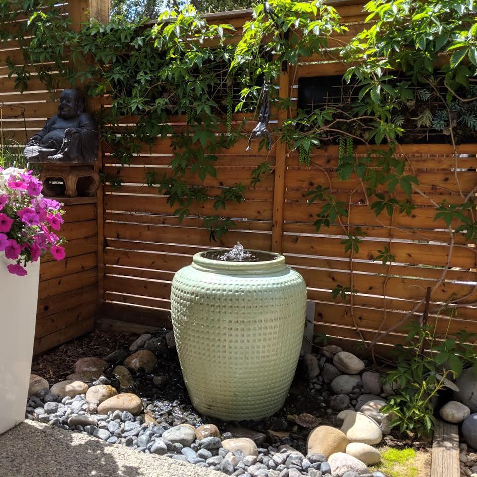 Green bubbler fountain surrounded by rocks. Photo by Instagram user @waterbydesign