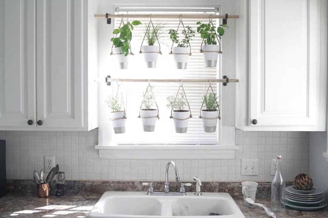 Hanging herb garden in white kitchen. Photo by Instagram user @hunkerhome
