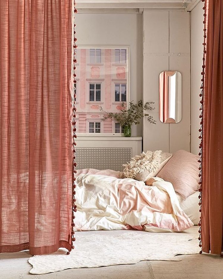 Pink curtains hiding bed area in studio apartment. Photo by Instagram user @urbanoutfittershome