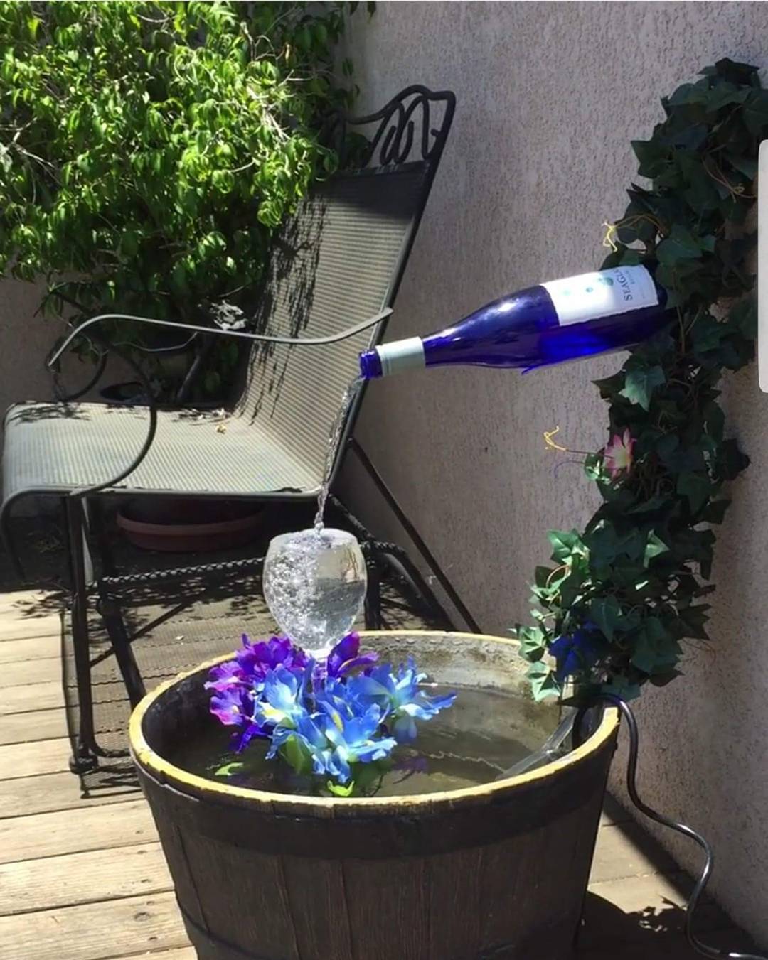 Porch fountain made from a blue wine bottle and wine glass. Photo by Instagram user @lisapalermorealtor