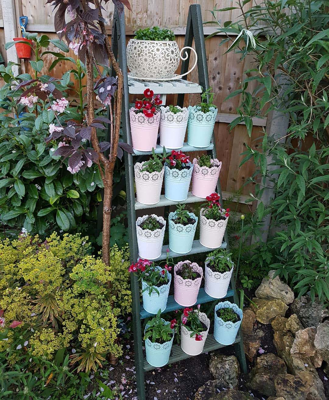 Decorate ladder with colorful metal pots and flowers. Photo via Instagram user @gpandhuman