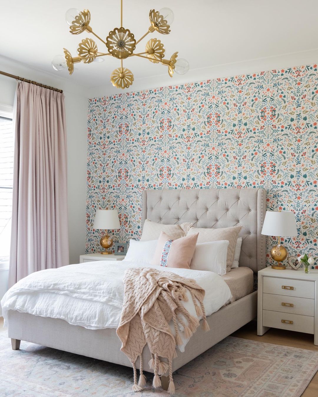 a bedroom with high ceilings and a large bed, the wall behind the bed has colorful, patterned wallpaper