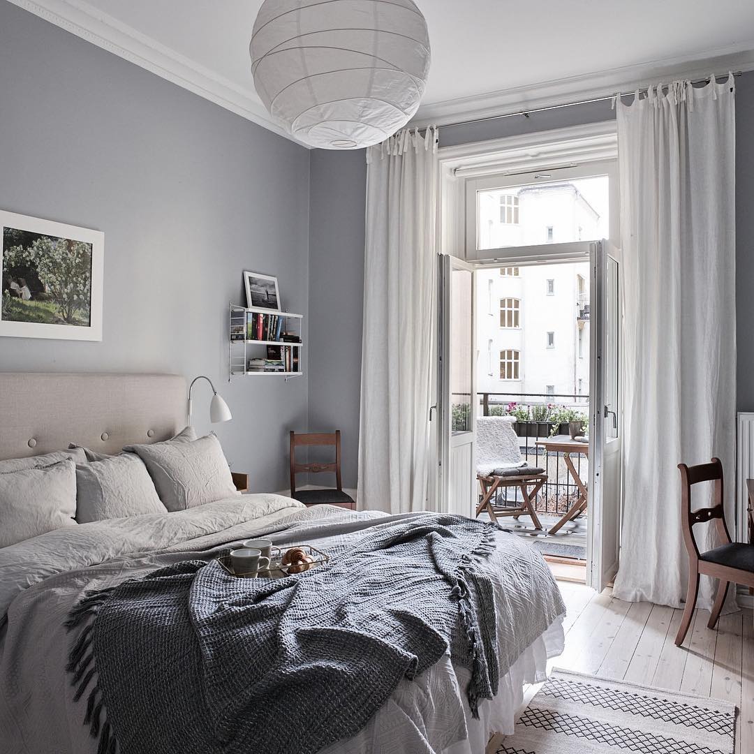 small apartment with bed and balcony door open with long curtains on either side photo by Instagram user @fboukari