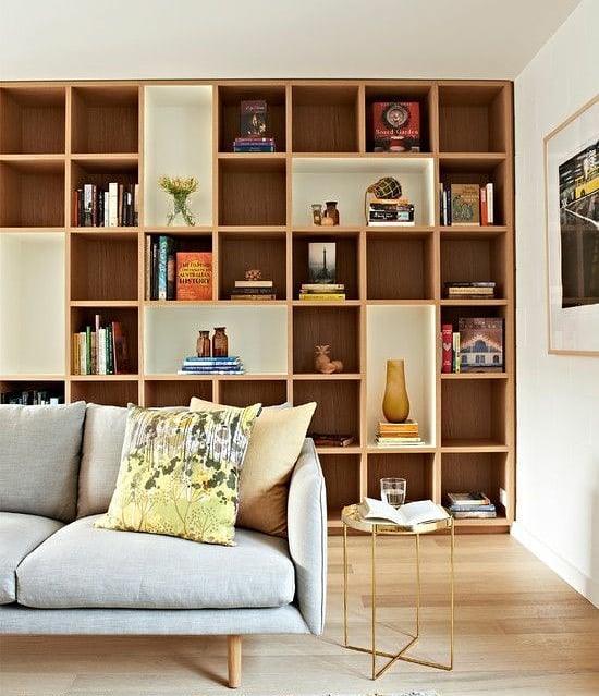 living room with large open shelves along the wall photo by Instagram user @zingdesignss