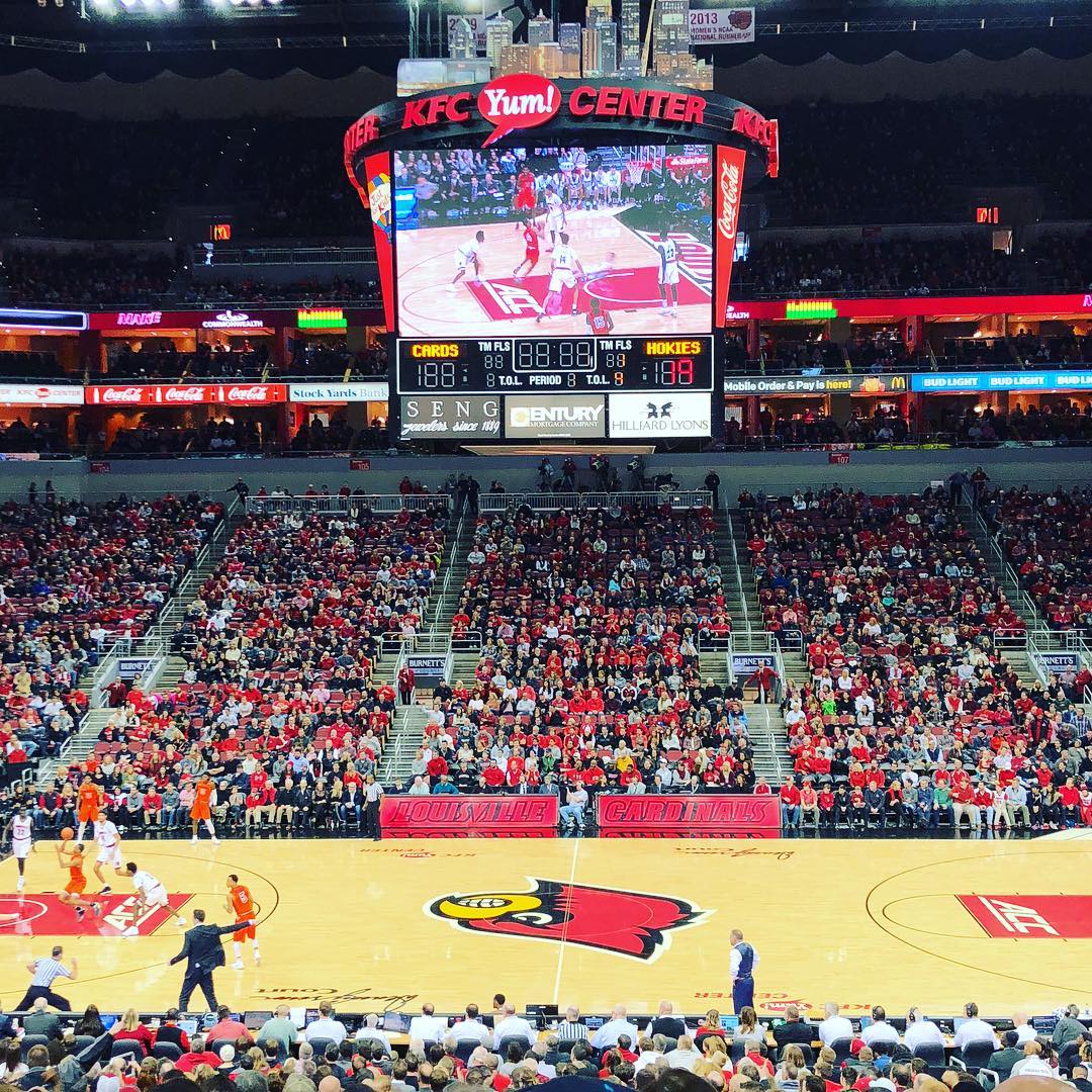 Looking down at the center Louisville basketball court and jumbotron during game. Photo by Instagram user @brigidkaelin
