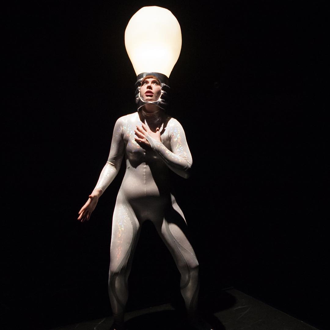 Woman in lightbulb costume acts out scene in play. Photo by Instagram user @brymerphoto