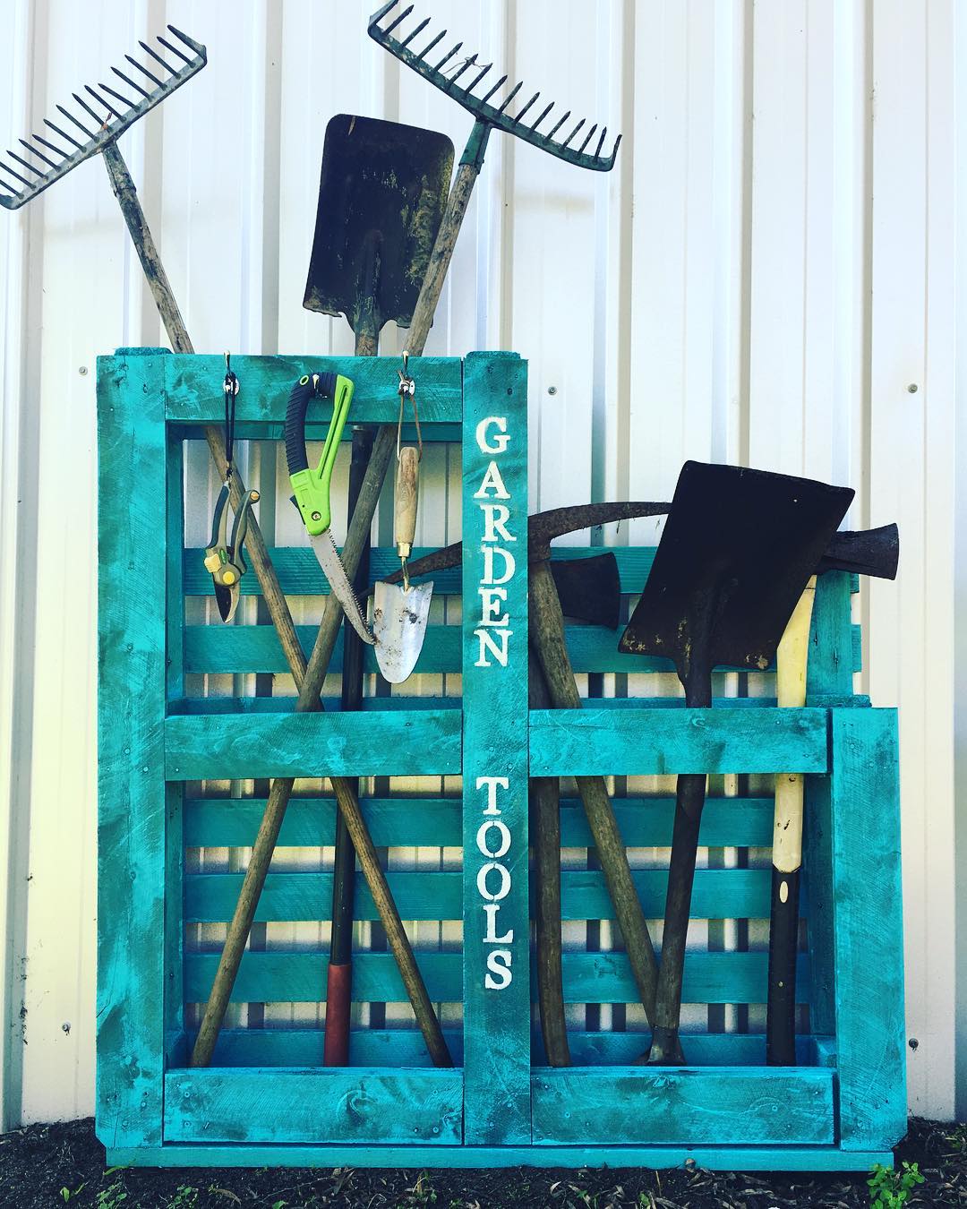 Blue wooden pallets holding garden tools.