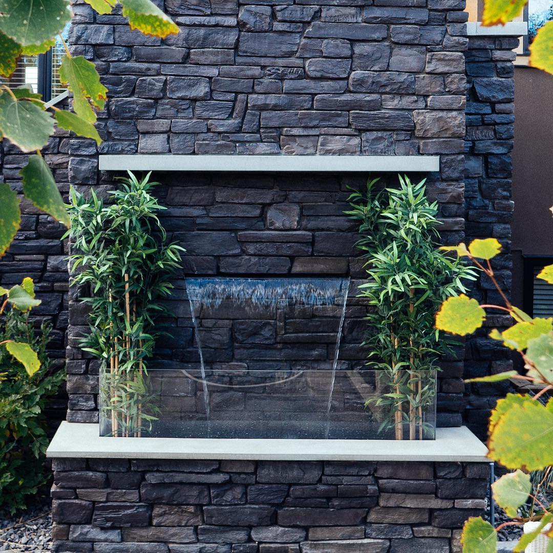 Water blade fountain on gray stone wall. Photo by Instagram user @waterbydesign